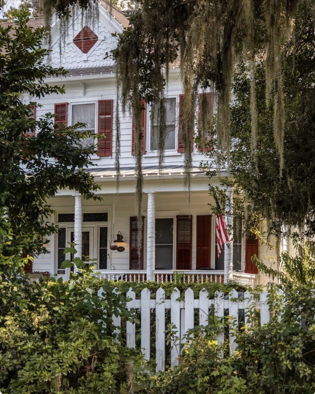 A white picket fence surrounds a house featuring red shutters, creating a charming and inviting exterior